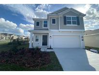 Two-story house with a gray exterior, two-car garage, and landscaped front yard at 768 Staffora St, Haines City, FL 33844