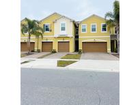 Two-story yellow townhome with attached garage and landscaping at 9831 Red Eagle Dr, Orlando, FL 32825