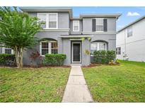 Two-story house with gray siding, black door, and landscaped lawn at 14236 Golden Rain Tree Blvd, Orlando, FL 32828