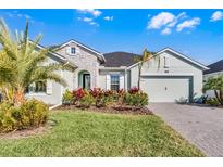 One-story home with light green exterior, landscaping, and paver driveway at 636 Mosaic Blvd, Daytona Beach, FL 32124
