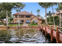 Waterfront home featuring a private dock, lush landscaping, and a charming two-story design with balcony at 10018 Lone Tree Ln, Orlando, FL 32836