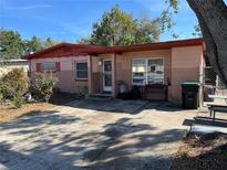 House exterior featuring a pink and red color scheme, driveway, and landscaping at 1607 Pontiac Ct, Orlando, FL 32808