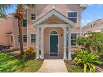 Inviting two-story home with a covered porch, a teal door and a lush, tropical landscape at 3013 Bonfire Beach Dr # 101, Kissimmee, FL 34746