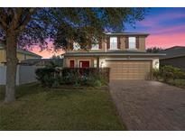 Two-story house with red accents, a brick driveway, and landscaping at 3720 Ryegrass St, Clermont, FL 34714