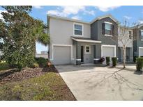 Modern two-story house with gray exterior, two-car garage, and landscaped front yard at 5427 Dragonfly Dr, Wildwood, FL 34785