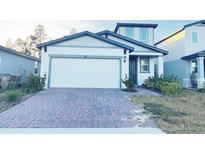 Two-story house with a two-car garage and a brick paver driveway at 849 Rivers Crossing St, Clermont, FL 34714
