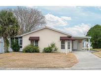 Tan single story home with carport and landscaped lawn at 1207 Palmetto Dr, Lady Lake, FL 32159