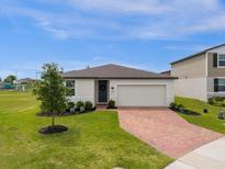 Single-story home with brick paver driveway and landscaped lawn at 1231 Citrus Landings Blvd, Davenport, FL 33837