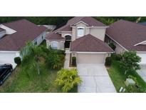 Two-story house with a brown roof, two-car garage, and palm trees in the front yard at 5086 Hook Hollow Cir, Orlando, FL 32837