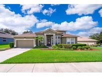 Beautifully landscaped front yard of a two-story home with a well-manicured lawn, shrubs, and a paver driveway at 1485 Whitefriar Dr, Ocoee, FL 34761