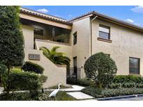 Inviting two-story condo with neutral stucco and a well-manicured landscape entrance with mature trees at 2865 Palermo Ct, Orlando, FL 32806