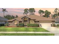 Brick house with a landscaped lawn and two-car garage at 340 Plantation Club Dr, Debary, FL 32713