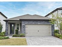 Charming single-story home featuring a two-car garage, stone accents, and a well-manicured lawn at 7958 Delwin Ln, Kissimmee, FL 34747
