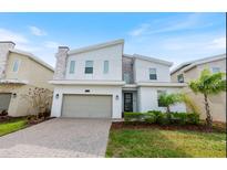 Two-story modern home with gray and white exterior, two-car garage, and landscaped lawn at 8828 Cruden Bay Ct, Davenport, FL 33896