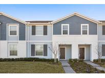 Two-story townhome with gray siding, dark brown doors, and a landscaped front yard at 1366 Lava Tree Dr, Davenport, FL 33897