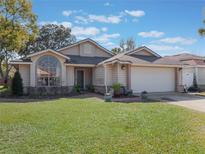 Tan single story house with a two car garage and manicured lawn at 349 New Waterford Pl, Longwood, FL 32779