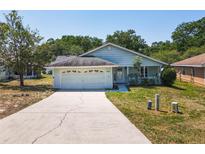 Charming single-story home with light blue siding, attached garage and inviting front yard at 511 Coventry Ct, Mount Dora, FL 32757