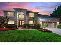 Two-story house with a three-car garage, landscaping, and a paved driveway at 13005 Islamorada Dr, Orlando, FL 32837