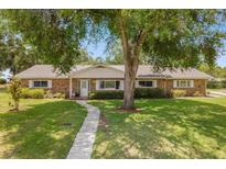 Brick ranch home with mature landscaping and a paved walkway at 134 W Sunset St, Groveland, FL 34736