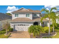 Charming two-story home with a well-manicured lawn, brick driveway, and lush landscaping with palm trees at 4455 Indigo Sky Ln, Kissimmee, FL 34744