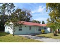 Charming single-story home featuring a red tile roof, a well-manicured lawn, and mature trees at 10614 Deergrass Ln, Orlando, FL 32821