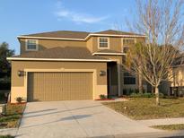 Two-story house with tan exterior, two-car garage, and landscaping at 2292 Grantham Ave, Davenport, FL 33837