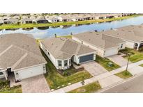 Aerial view of a modern single-Gathering home in a waterfront community with lush landscaping and a gray colored driveway and garage door at 2496 Pine Preserve Ct, St Cloud, FL 34771