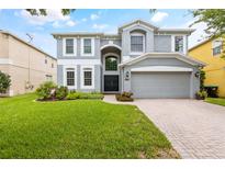 Two-story house with gray siding, a three-car garage, and a well-manicured lawn at 12666 Moss Park Ridge Dr, Orlando, FL 32832