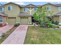 Tan two-story townhome with two-car garage and landscaped front yard at 2311 Chatham Place Dr, Orlando, FL 32824