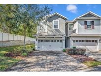 Two-story townhome with gray exterior, two-car garage, and a brick paved driveway at 1196 E 10Th St, Apopka, FL 32703