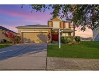 Two-story house with a tan exterior, attached garage, and landscaping at 13041 Boggy Pointe Dr, Orlando, FL 32824