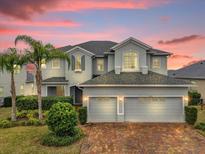 Elegant two-story home boasts a three-car garage, lush landscaping, and a brick driveway at 16737 Meadows St, Clermont, FL 34714