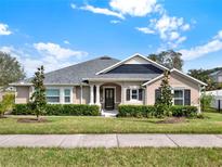 Tan house with gray roof, landscaping, and black shutters at 2583 Grassmoor Loop, Apopka, FL 32712
