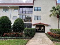 Charming condo complex featuring a stucco facade, red tile roof, lush landscaping, and gated entry for added security at 535 N Interlachen Ave # 203, Winter Park, FL 32789