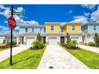 Charming townhomes feature colorful exteriors, well-manicured lawns, and paved driveways under a sunny sky at 7925 Putting Green Way, Reunion, FL 34747