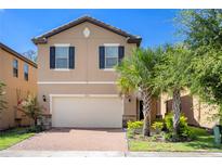 Two-story house with a beige facade, a brick driveway, and lush landscaping at 8896 Bengal Ct, Kissimmee, FL 34747