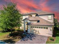 Two-story house with a three-car garage and a landscaped front yard at 9024 Shadow Mountain St, Davenport, FL 33896