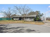 Gray brick ranch house with mature trees, a shed, and a large yard at 1201 Carol Ave, Auburndale, FL 33823