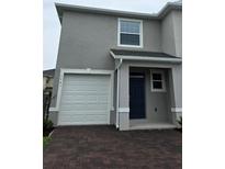 Charming two-story home featuring a one car garage and a neatly bricked driveway at 1541 Isleta Loop, Kissimmee, FL 34741