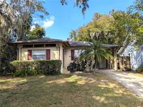 Charming bungalow featuring a well-manicured lawn, mature trees, and a convenient carport at 1825 Park Lake St, Orlando, FL 32803