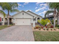 Charming single-Gathering home with a two-car garage, brick driveway and tropical landscaping at 213 Caryota Ct, New Smyrna Beach, FL 32168