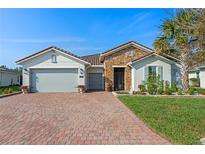 Charming single Gathering home featuring a brick driveway, stone accents, and manicured landscaping at 442 Treviso Dr, Poinciana, FL 34759