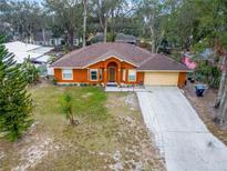 Orange house with brown roof, driveway, and yard, seen from above at 5422 Reata Way, Orlando, FL 32810