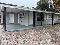 Newly renovated home with gray exterior, brick paver driveway, and covered entryway at 5640 Chet Dr, Orlando, FL 32818