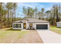 New construction home with white facade, dark gray roof, and a spacious driveway at 6732 Sw 132Nd St, Ocala, FL 34473