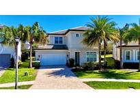 Two-story home featuring a two-car garage, stone accents, well-manicured lawn, and mature palm trees at 10680 Royal Cypress Way, Orlando, FL 32836