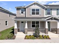 Charming two-story townhome featuring a covered front porch with stone accents and manicured landscaping at 1309 Coral Bean Ln, Winter Springs, FL 32708