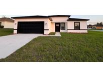 Modern home featuring a black garage door and a well-manicured lawn at 150 Marion Oakes Trl, Ocala, FL 34473