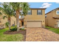 Two-story house with tan siding, brick accents, and a two-car garage at 1505 Mumbai Way, Kissimmee, FL 34747