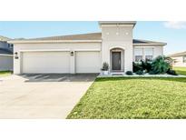 Two-car garage and well-maintained lawn characterize this home's exterior at 157 Pineywoods St, St Cloud, FL 34769